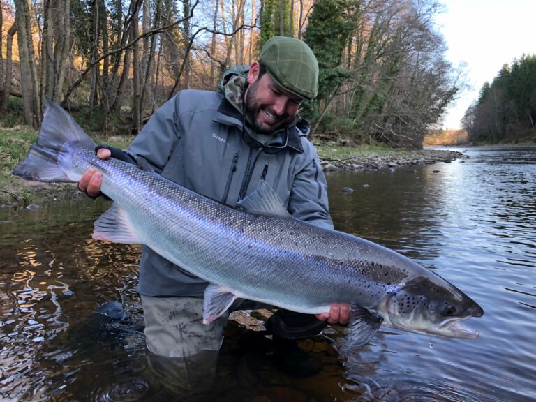 A man holding a large fish in a river.