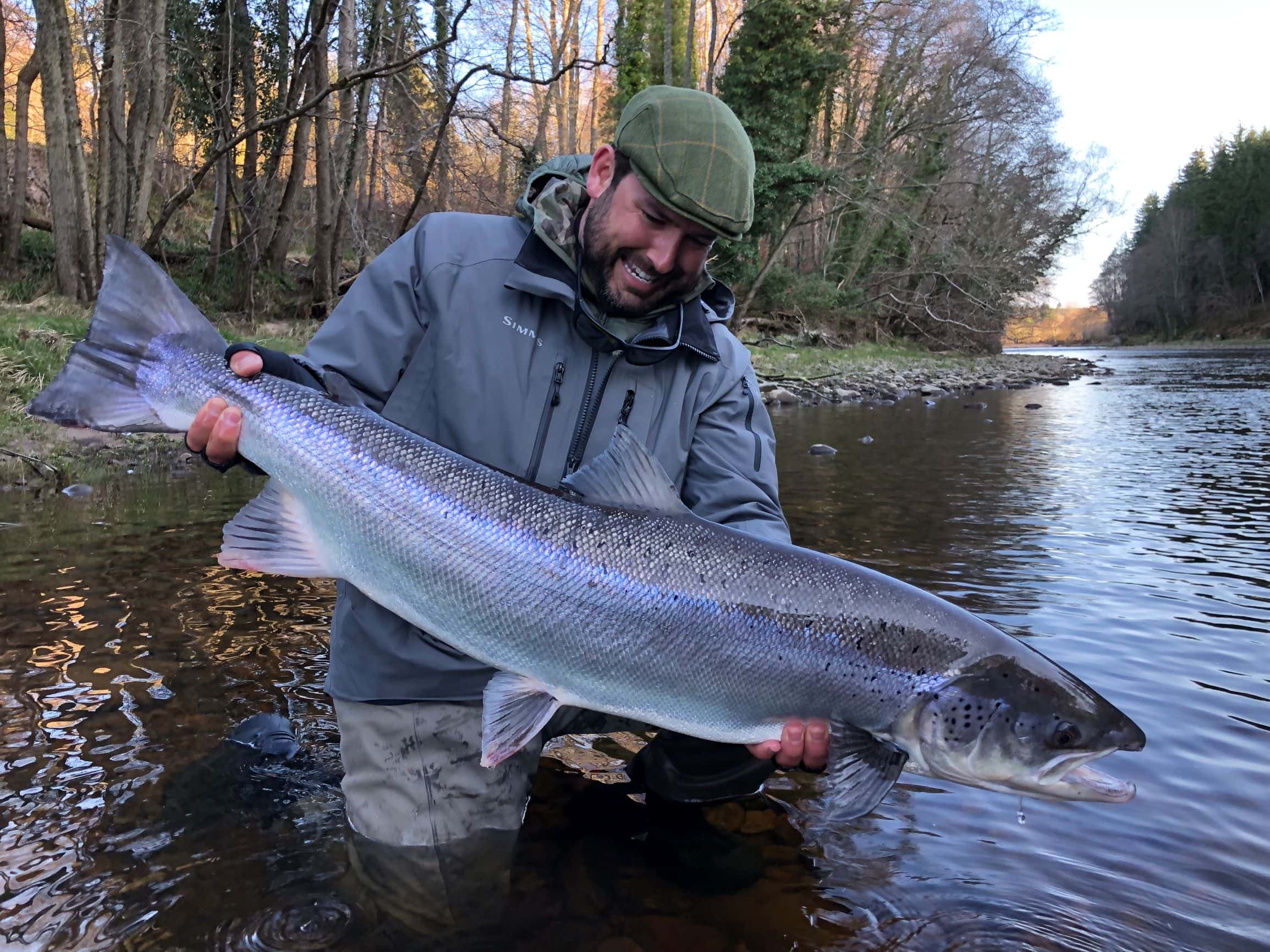 A man holding a large fish in a river.
