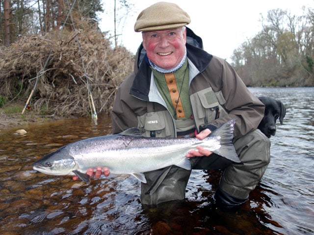 A speycaster holding a fish in a river.