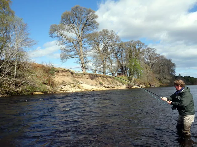 A man is Speycasting in a river.