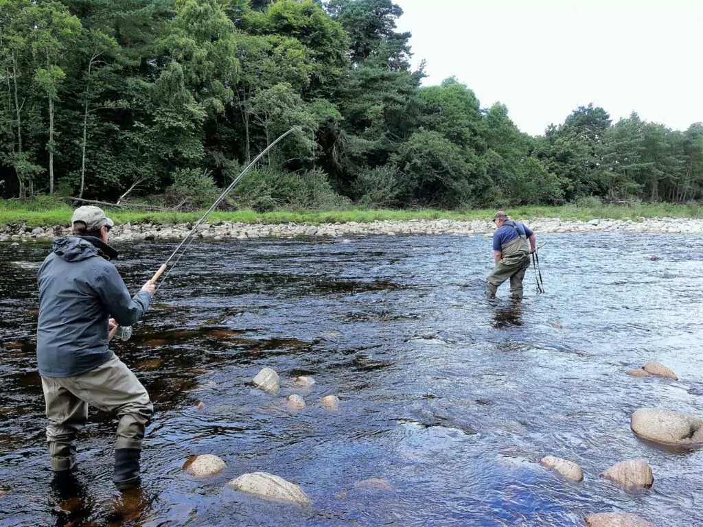 Two men fly fishing in a river.