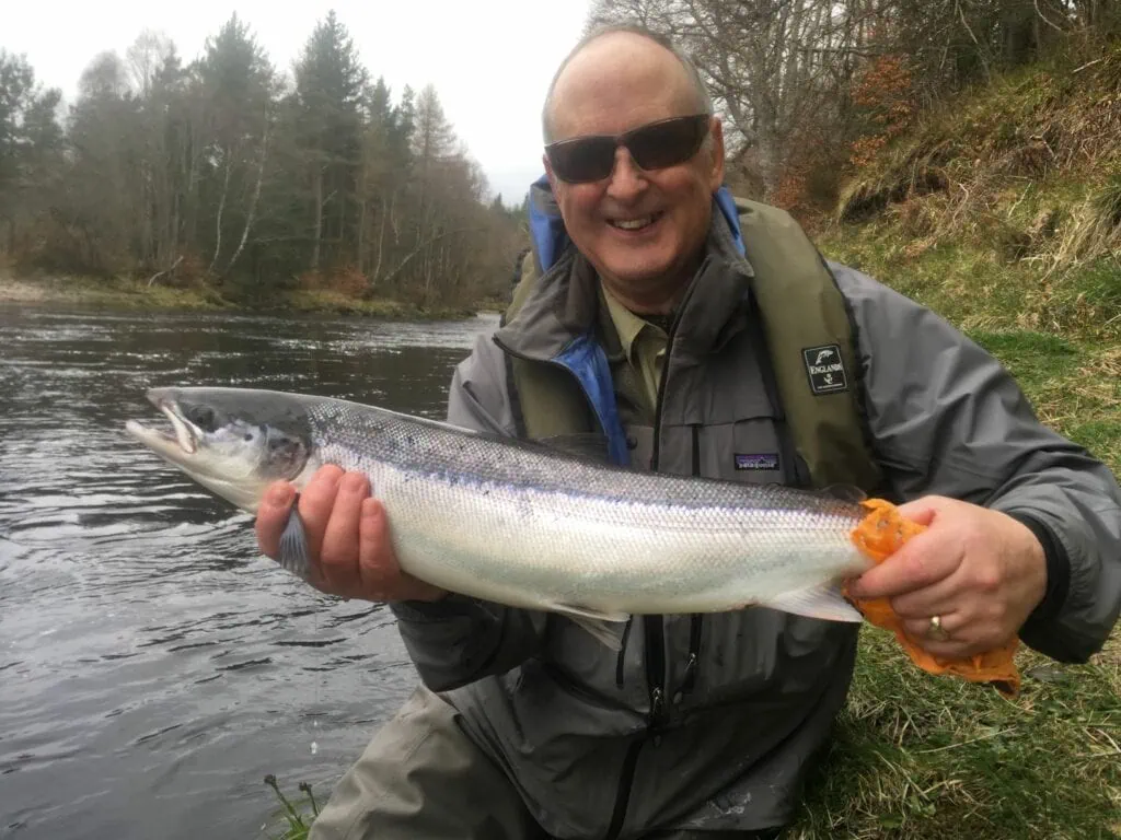 A man holding up a fish on a river.