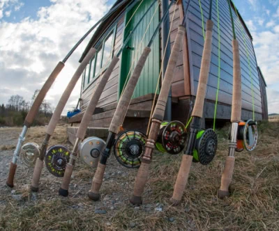 A group of fishing rods leaning against a wooden cabin.