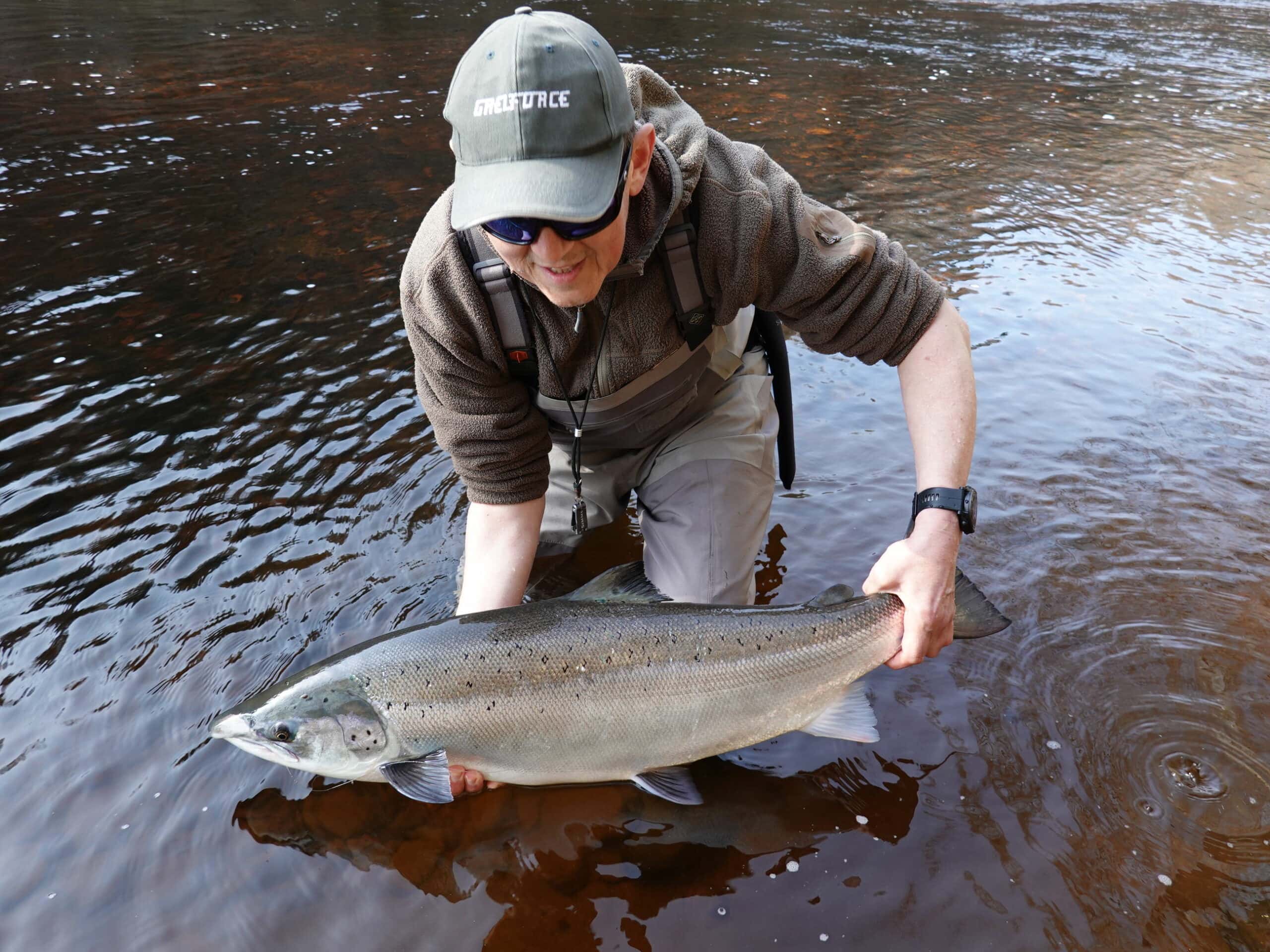 A man holding a fish in a river.