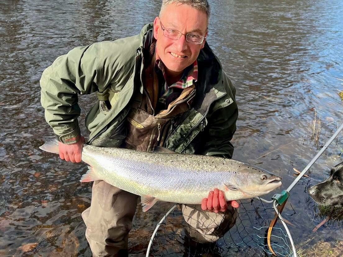 A man holding up a fish in a river.