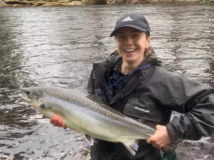 A woman holding a fish in a river.
