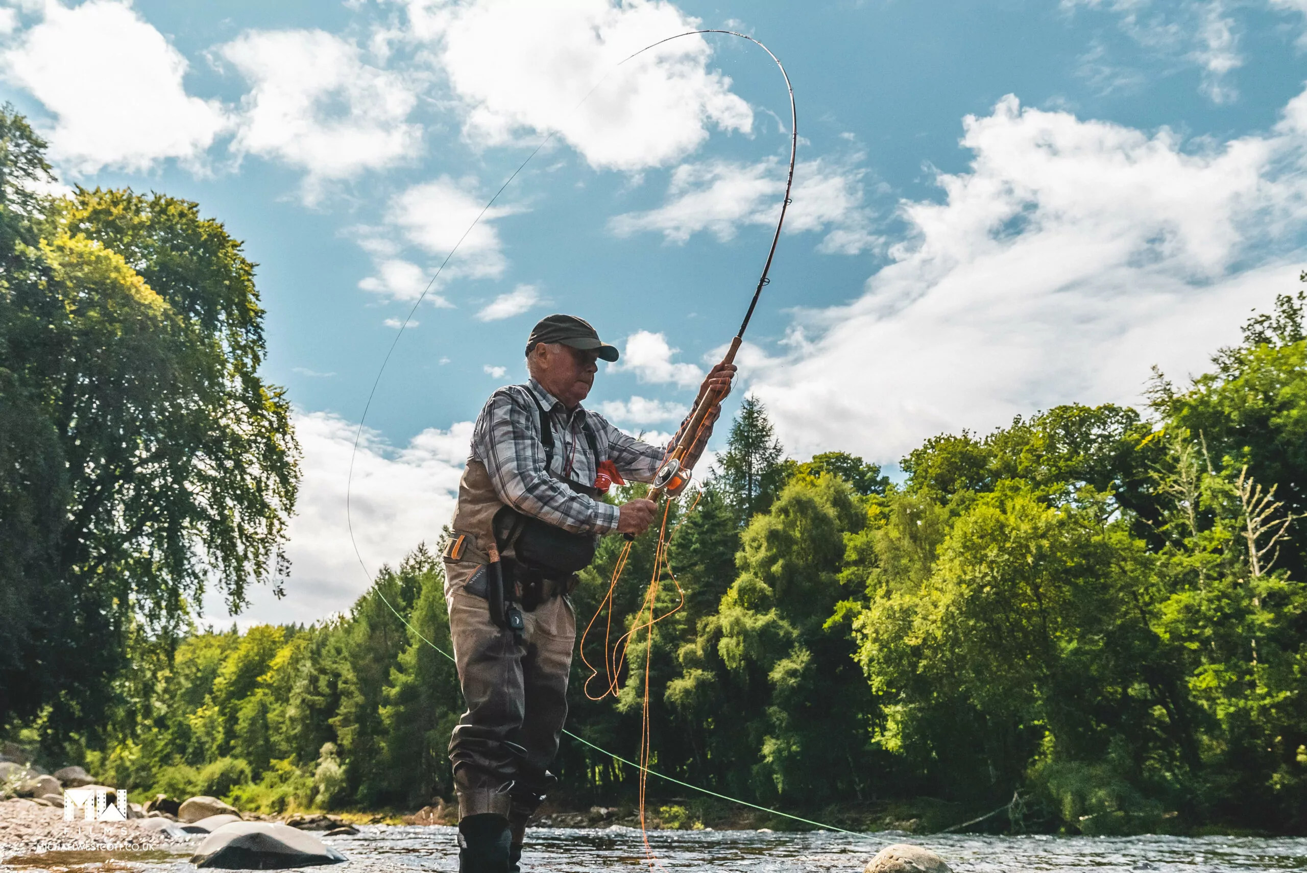 A man is fishing in a river with a fly rod.