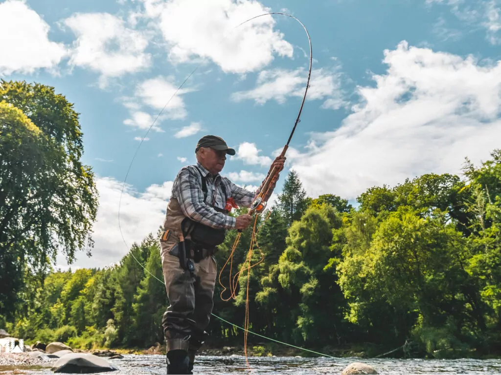 A man is fly fishing on a river in scotland.
